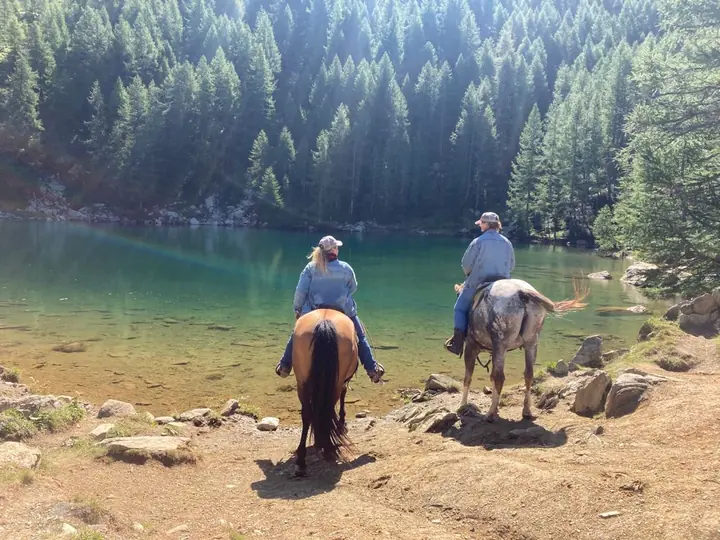 Due cavalieri sulla riva del lago alpino